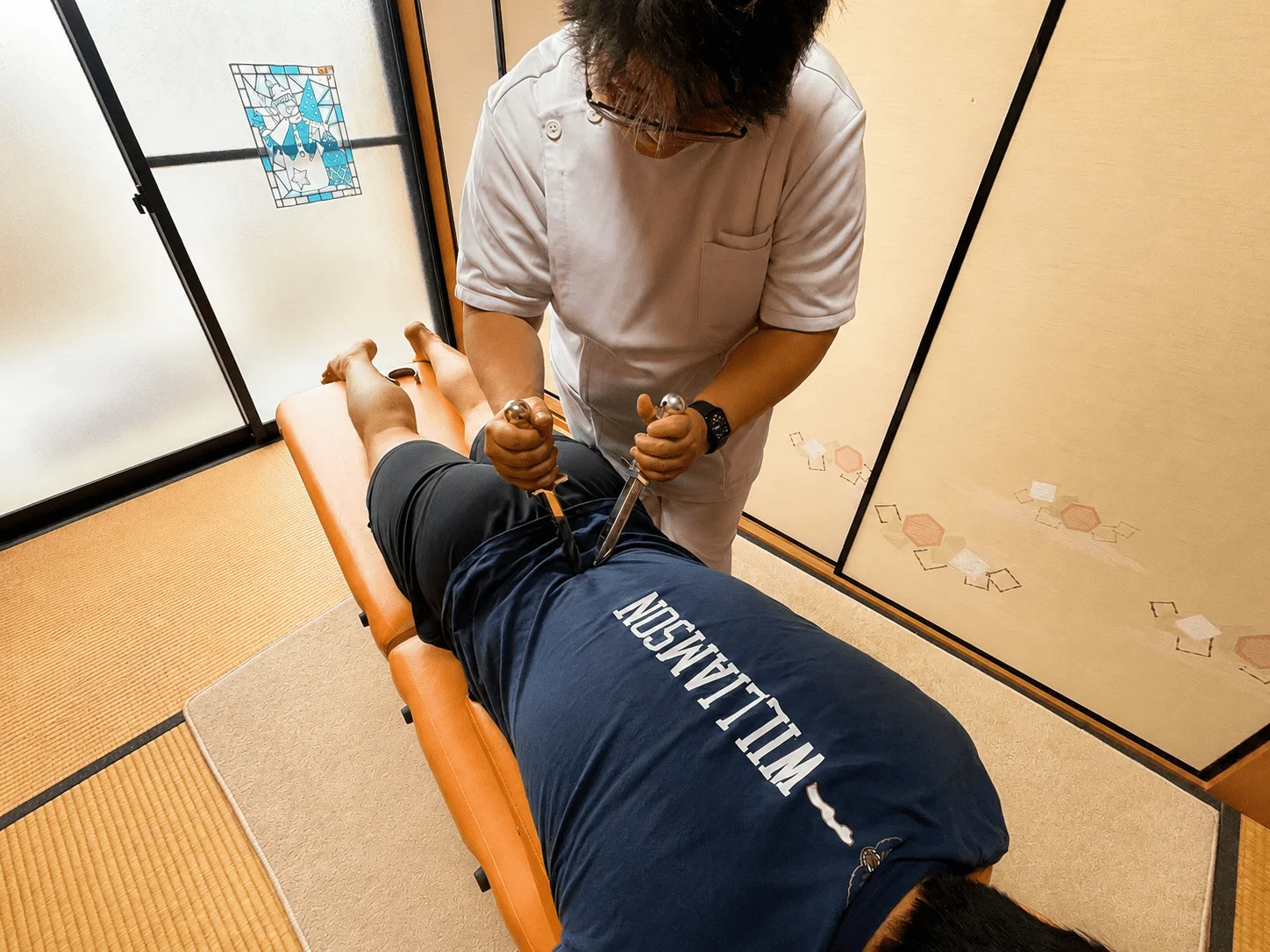 仰向けで全身のバランスを見ながら骨盤まわりを丁寧に整える施術風景